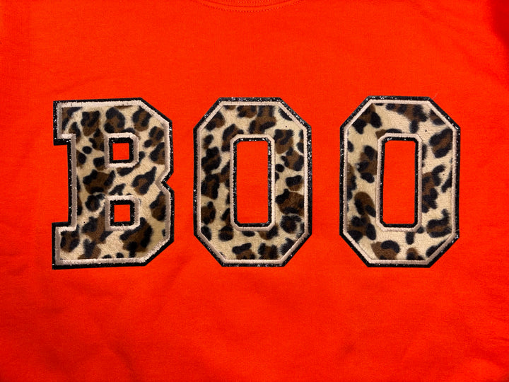 Leopard letters edged in glitter on an orange sweatshirt